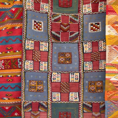 A quilt of varied patterns, in reds and oranges and blues.